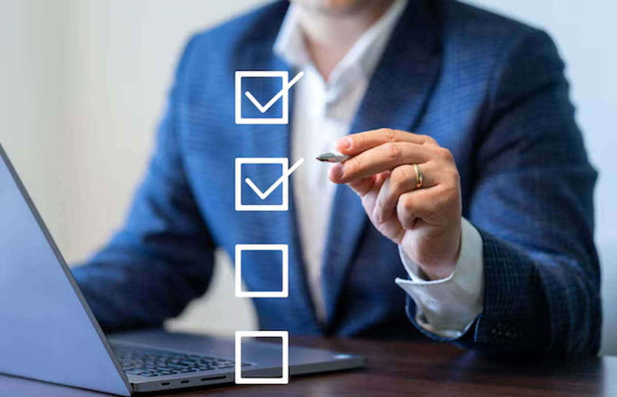 A professional in a formal suit manages a digital task list on his laptop, checking off completed tasks.