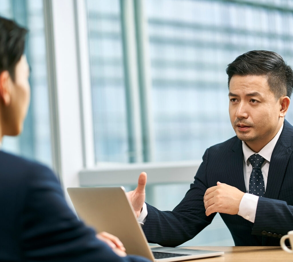 Business scene where two men are having a discussion with a laptop in front of them.