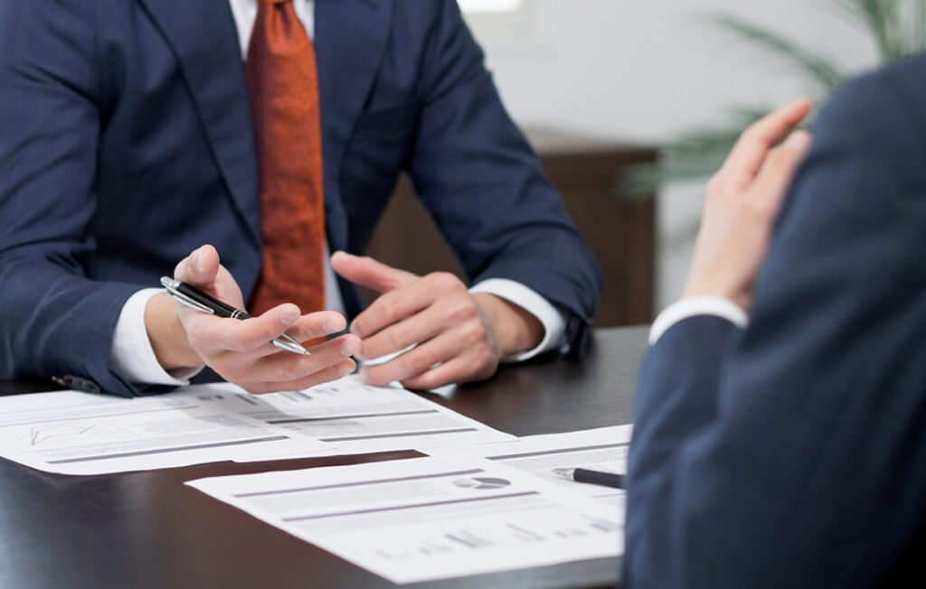 Business scene with two professionals discussing over documents, with one pointing at the papers.