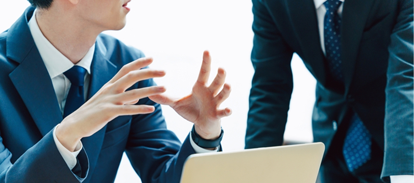 Business executives in suits discussing during a meeting, exchanging ideas with expressive hand gestures.
