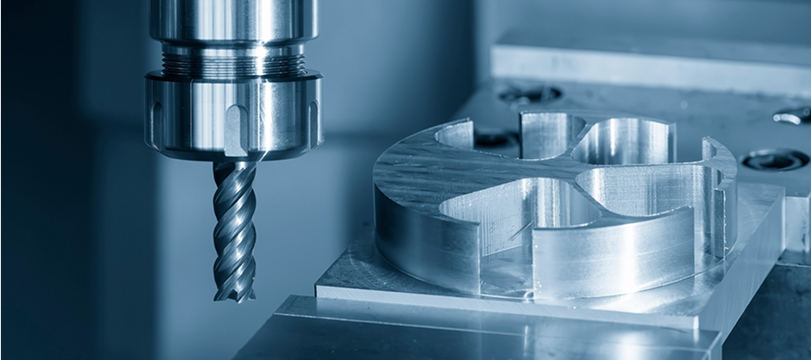 CNC machine cutting a metal part with a rotating drill for precision manufacturing.