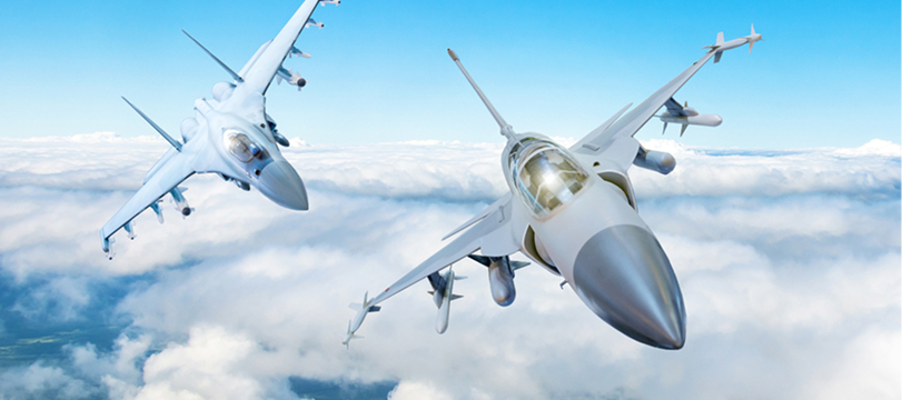 Two fighter jets flying above the clouds in a clear blue sky symbolizing speed and advanced aviation technology.