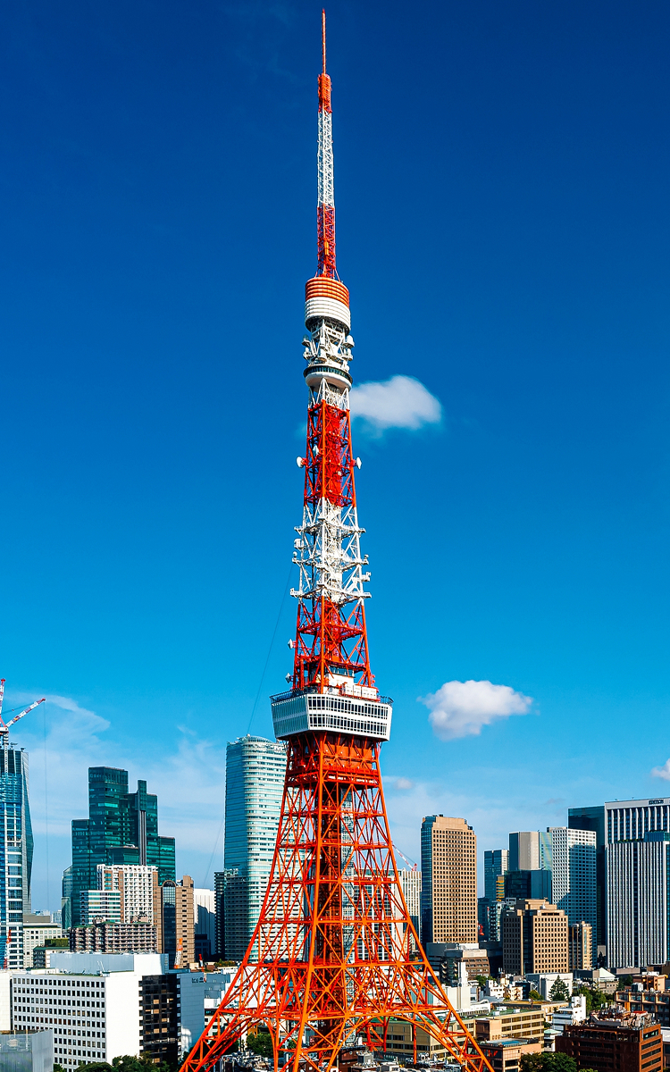 東京の摩天楼に囲まれた東京タワーが、澄み切った青空の下に浮かび上がる。